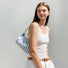 Model wearing the striped baguette bag as an underarm shoulder bag for a summer look.