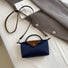 Navy blue mini nylon bag flat lay on white desk, showing the removable long strap.