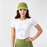 Model styling a bright green quick dry cap for a functional gorpcore outfit with an athletic top.