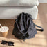 Detailed flatlay of the black nylon bucket bag showing its drawstring closure.