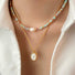 Model wearing two necklaces as layer style, one is aqua beads necklace and one is gold jade.