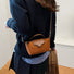 Detailed shot of a model holding the ocher mini nylon bag by its leather handle.