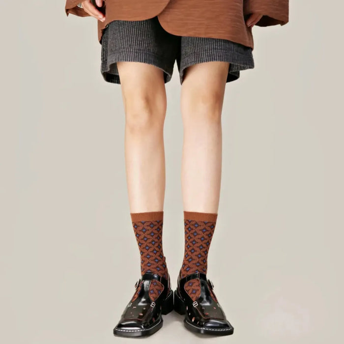 Model wearing a pair of brown socks with a blue diamond pattern.