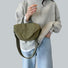 Model holding the olive green crinkle nylon bag as a casual carry.