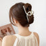 Model wearing a large pearl hair claw in a low bun; elegant hair accessory for long thick hair.