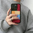 Hand holding a black silicone case with colorful polyester textile patches. Vibrant playful design.