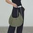 Model carrying an olive green nylon  crescent bag handheld , ideal for city walks and gifting.