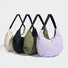 Four pleated nylon crescent shoulder bags in beige, black, olive, and light purple with black straps.