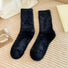 Angled view of black plush cozy socks on a textured beige surface.