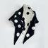 Flatlay view of black and white double-sided polka dot knit scarf.