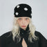 Model wearing black and white polka dot knit scarf as a headscarf.