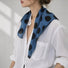 Model wearing soft blue polka dot silk scarf with white shirt.