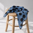 Blue polka dot silk scarf displayed on a wooden stool.