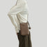 Model carrying a brown Polycolor hanging ball leather bag as crossbody, easy for commuting and weekends.