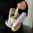 Hands holding open purple Puffy Candy triangle mini bag; quilted zip organizer with mesh pocket for makeup.