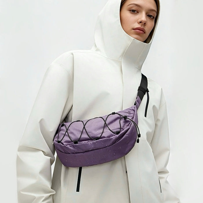 A women wearing a lilac purple  nylon sling bag as crossbody, showcasing sleek crescent silhouette and water-resistant fabric.