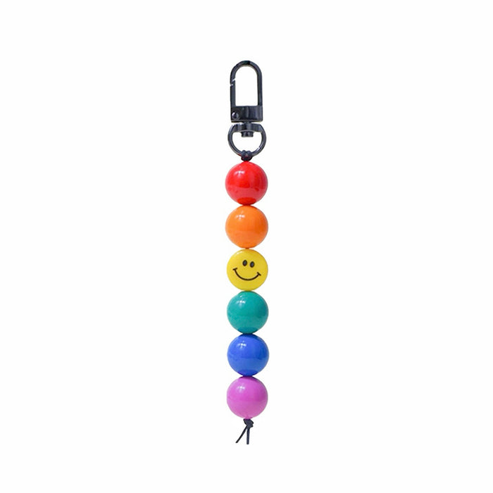 Rainbow acrylic bead bag charm with a yellow smiley face bead and black clip.