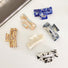 Angled view of six rectangle acrylic hair claws in various marbled colors.