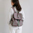 Back view of a model wearing the pink and green plaid laptop backpack flat against the lower back.