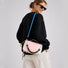 Back view of a model carrying the reversible pink and navy blue nylon utility crossbody bag.