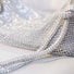Angled view of a sparkling silver rhinestone hobo bag, showcasing its shimmering material and intricate design.
