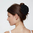 Side view of a model styling a classic black fabric rose hair claw with a pearl necklace.