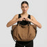 Model holding the brown canvas tote bag by the top handles.