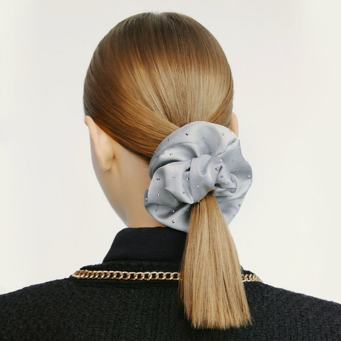 Light gray satin scrunchie with rhinestones on a blonde ponytail.