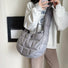 Model wearing a large grey padded crossbody bag; lightweight puffer sling bag for urban commute.