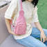 Pink corduroy sling bag with adjustable strap worn by a person in a casual setting.