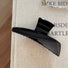Flat lay of Sleek Curved Hair Claw  in black, easy for workdays and special occasions.