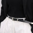 Minimalist leather belt styled with white formal high-waisted trousers.