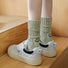 Model wearing a pari of Smile Slouch Socks in olive green, great for daily wear and lounging.