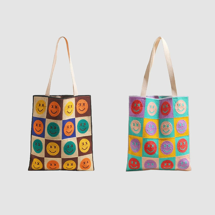 Two knitted tote bags, one brown plaid with colorful smiley faces, the other multi-color plaid with smiley faces.