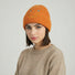 Model wearing Smiley Ribbed Knit Beanie in orange. Warm and soft ribbed knit for cold-weather comfort.