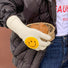 Model wearing smiling round face gloves in white, plush knit with smile patch; cute warmth for winter days.