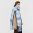 Model wearing a plaid polyester scarf in teal, easy for weekend styling and gifting.