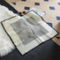 Full view of the black and white square pattern silk scarf laid flat.