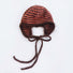 Orange and brown striped earflap hat with a minimalist and cozy knit design.