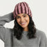 Smiling woman wearing a coral pink and brown striped fluffy knit beanie for a cozy winter look.