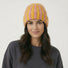 Model wearing Striped Fluffy Knit Beanie in yellow coral. Bold colorful stripes in a breathable knit finish.