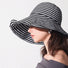 Side view of Model wearing Striped Wide Brim Bucket Hat in black, showcasing the protective wide brim.