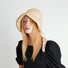 Fashion shot of the cream yellow sun shield hat paired with a black summer dress.
