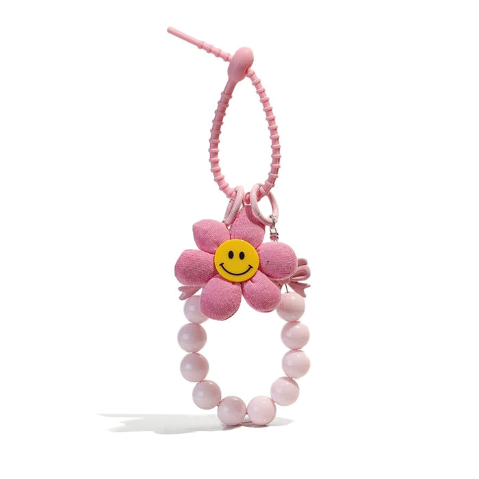 Pink polyester flower bag charm with a yellow smiley face, beaded wristlet, and removable elements.