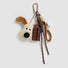 Close-up of the Super Dog plush bag charm with carabiner, ropes and chocolate.