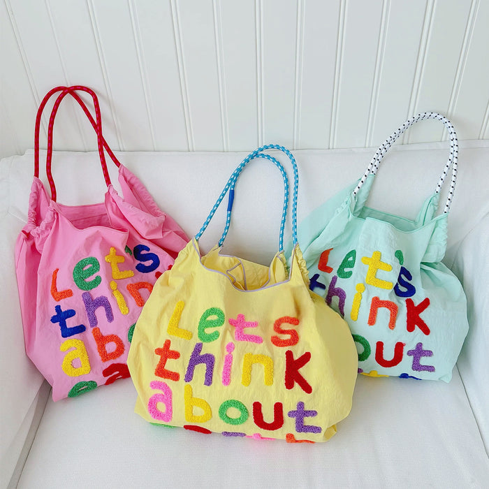 Three cotton "Think About Earth" tote bags in pink, yellow, and mint green with colorful embroidered text.