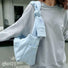 Light blue cotton-nylon Twist & Tie Sleeve Bag with knotted strap, zip-top, and outer slip pockets.