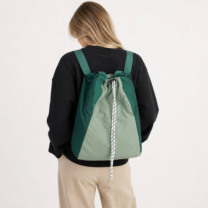 Back view of a model wearing the green two-tone ultralight 2-way drawstring backpack.