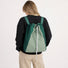 Back view of a model wearing the green two-tone ultralight 2-way drawstring backpack.