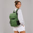 Model wearing the forest green flap laptop backpack on a city commute.